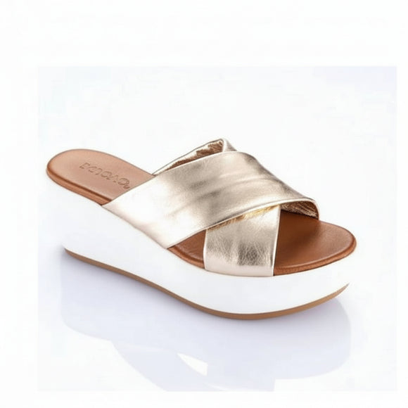 A single women's platform slide sandal with metallic gold crisscross straps, a brown footbed, and a thick white wedge heel, shown on a white background with a soft reflection.