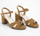 A pair of tan block-heel sandals with crisscross front straps and ankle straps, shown on a clean white background.
