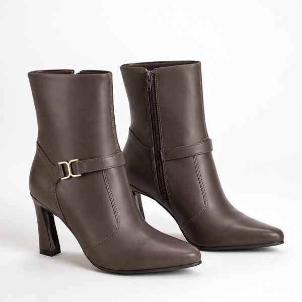 A pair of dark brown leather ankle boots with pointed toes, block heels, side zippers, and a decorative strap with a gold buckle on the outer side, shown against a plain white background.