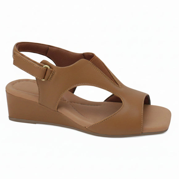 A tan wedge sandal with cutout details and an ankle strap, shown from a side profile on a white background. A 'Genuine Leather' graphic is visible in the top right corner.