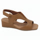 A tan wedge sandal with cutout details and an ankle strap, shown from a side profile on a white background. A 'Genuine Leather' graphic is visible in the top right corner.