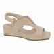 A beige wedge sandal with cutout details and an adjustable ankle strap, shown from a side profile on a white background. A graphic badge in the top right corner reads 'GENUINE LEATHER'.