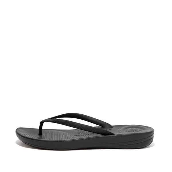 FitFlop iQushion All Black flip-flop, side view showing toe-post straps and textured footbed