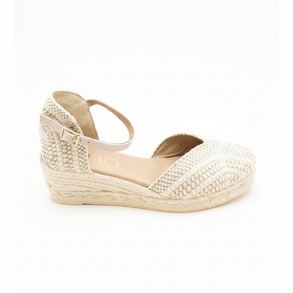A single women's wedge espadrille sandal in a light beige/cream color, featuring a woven upper and a braided jute wedge heel, shown against a plain white background.