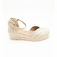 A single women's wedge espadrille sandal in a light beige/cream color, featuring a woven upper and a braided jute wedge heel, shown against a plain white background.